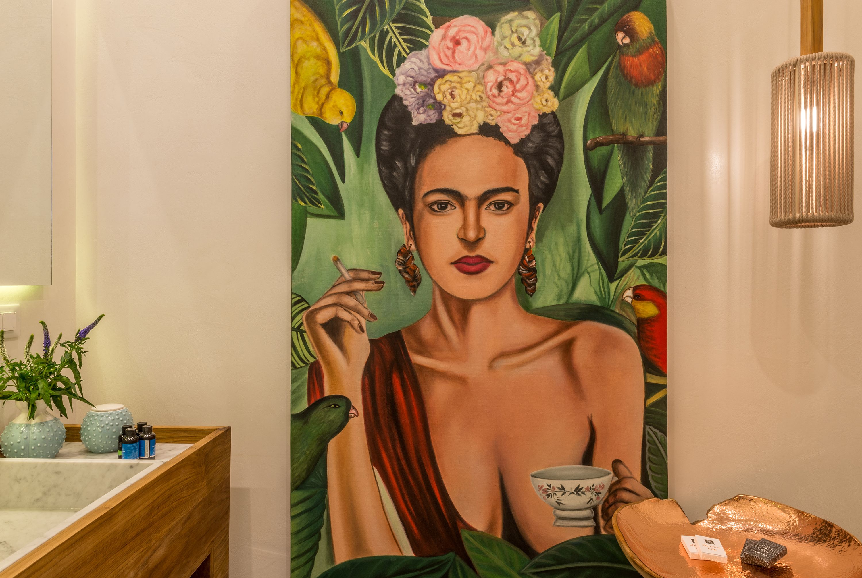 A bathroom with a large mural, a wooden vanity, a mirror, and a hanging light fixture.