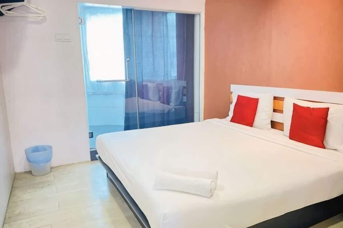 Ein Hotelzimmer mit einem Bett, einem Fenster und einer Tür, die auf einen Balkon führt.