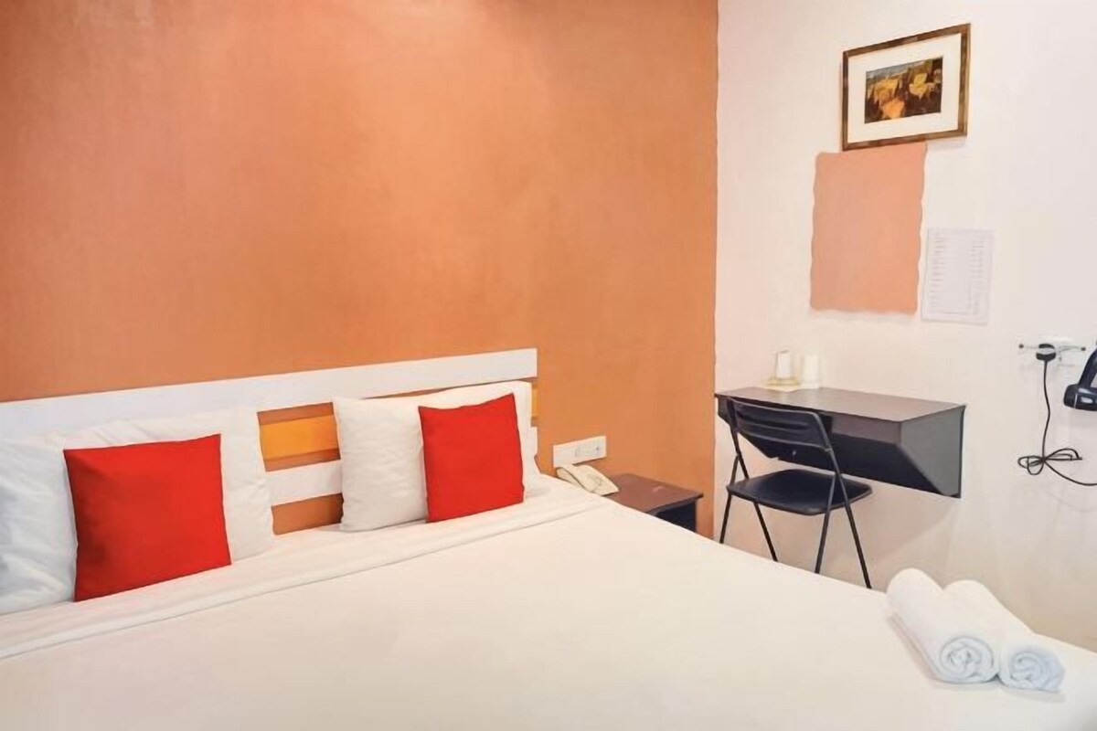 Een hotelkamer met een bed, een bureau, een stoel en een klein tafeltje met een lamp.