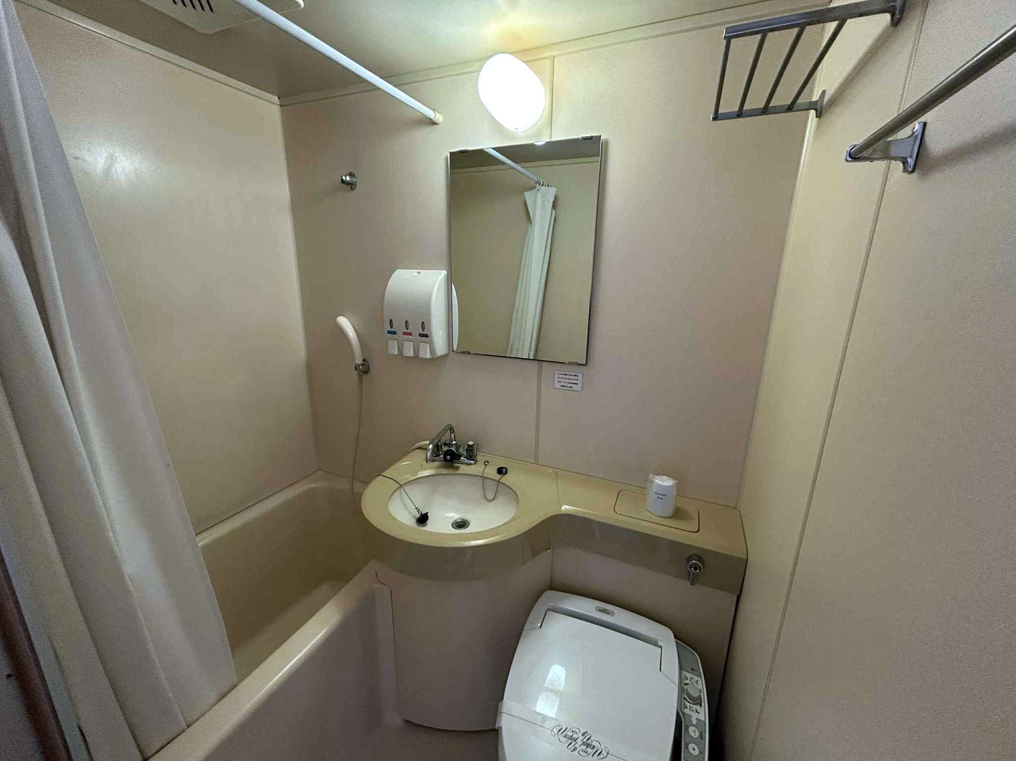 Un baño pequeño con lavamanos, espejo, dispensador de toallas y retrete.