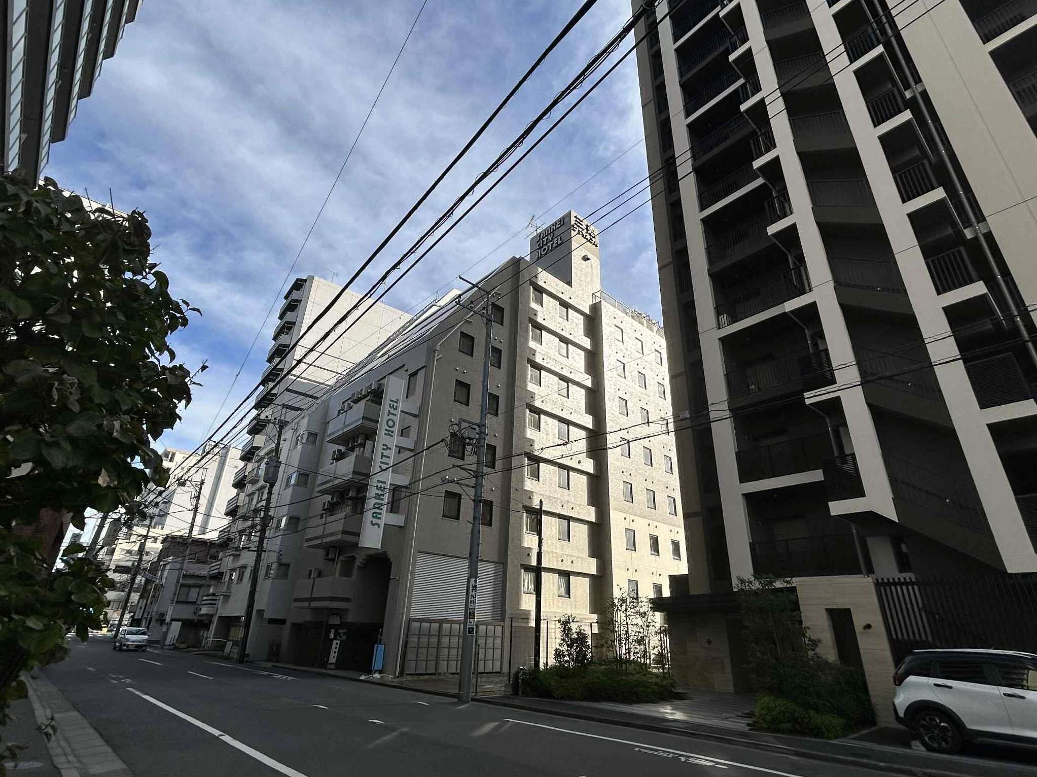 Un edificio de varios pisos que muestra un letrero que indica que es un hotel. Se observan varios pisos con balcones y ventanas. El edificio presenta un estilo arquitectónico moderno, con techo plano y una combinación de tamaños de ventanas.