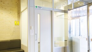 A reception area with a wooden wall, a white door, a glass partition, and a bench. - Sankei City Hotel Hachiouji (Hachioji)