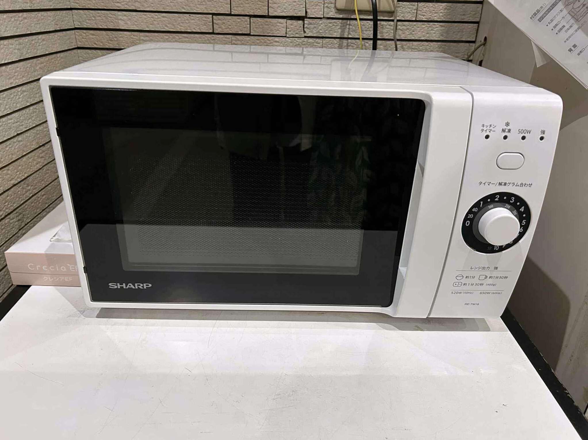 A white Sharp microwave oven with a black door, a control panel with a dial, and a power indicator.