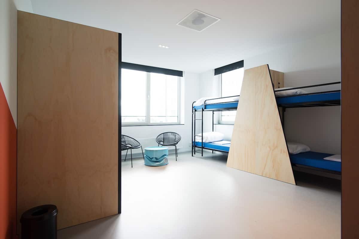 A room with bunk beds, a window, and a chair.