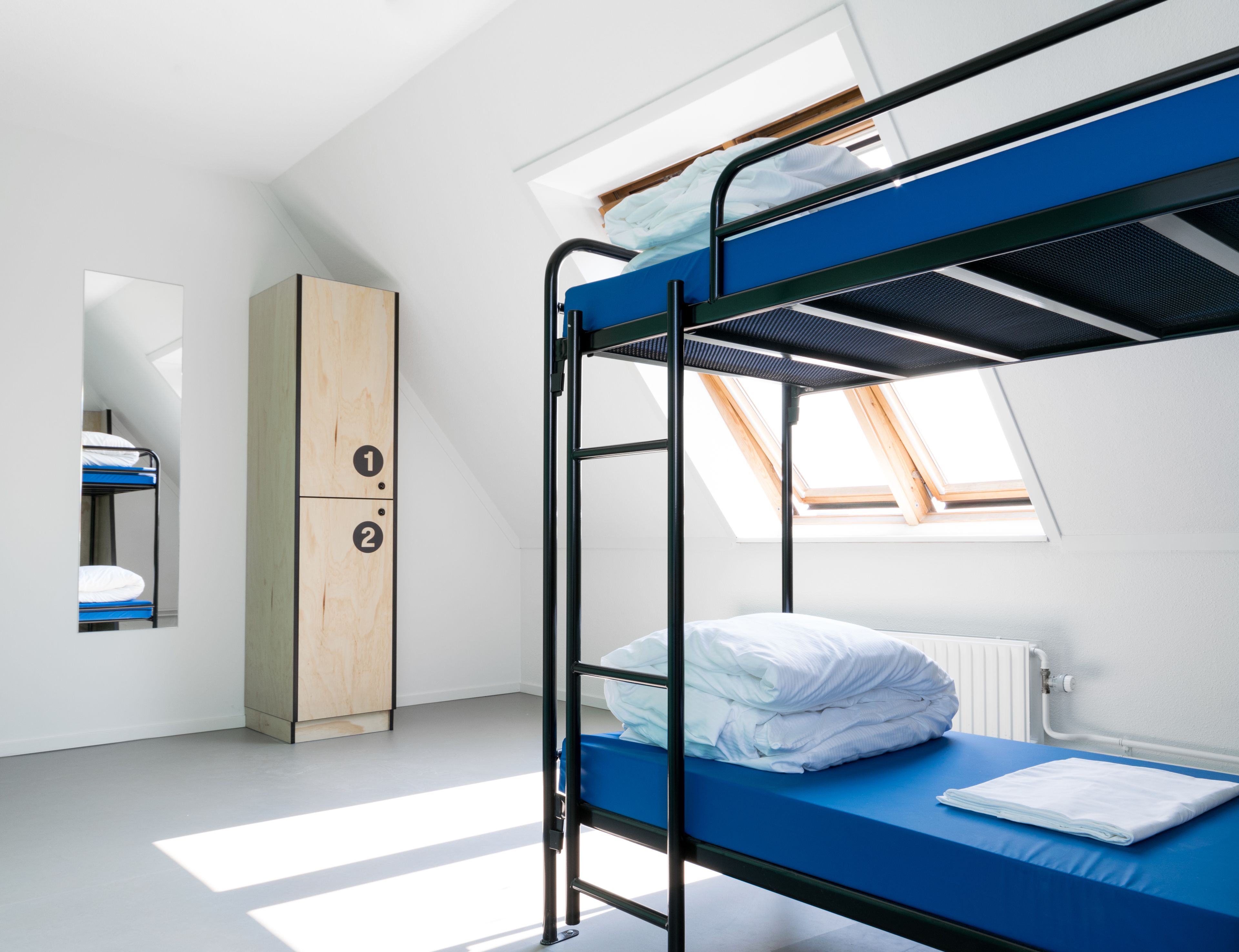 Un dormitorio con literas, un armario de madera y tragaluces.
