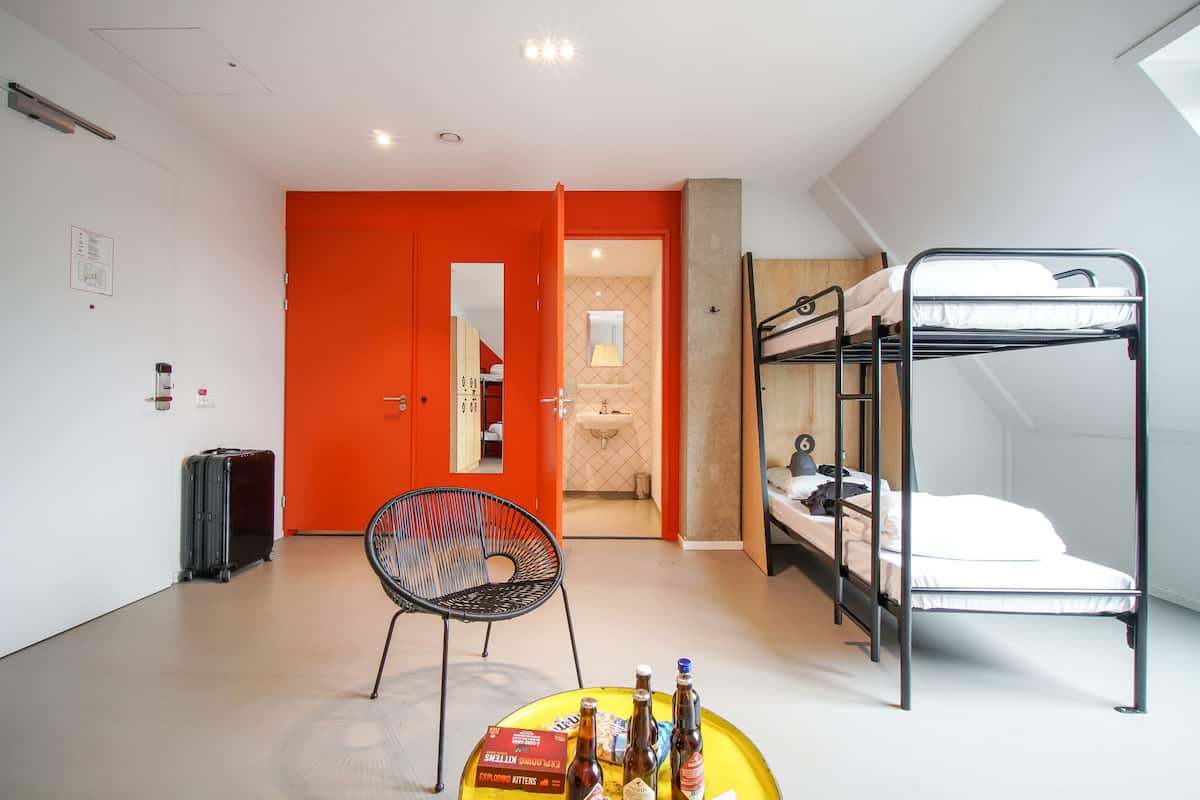 A room with a bunk bed, a suitcase, and a chair.