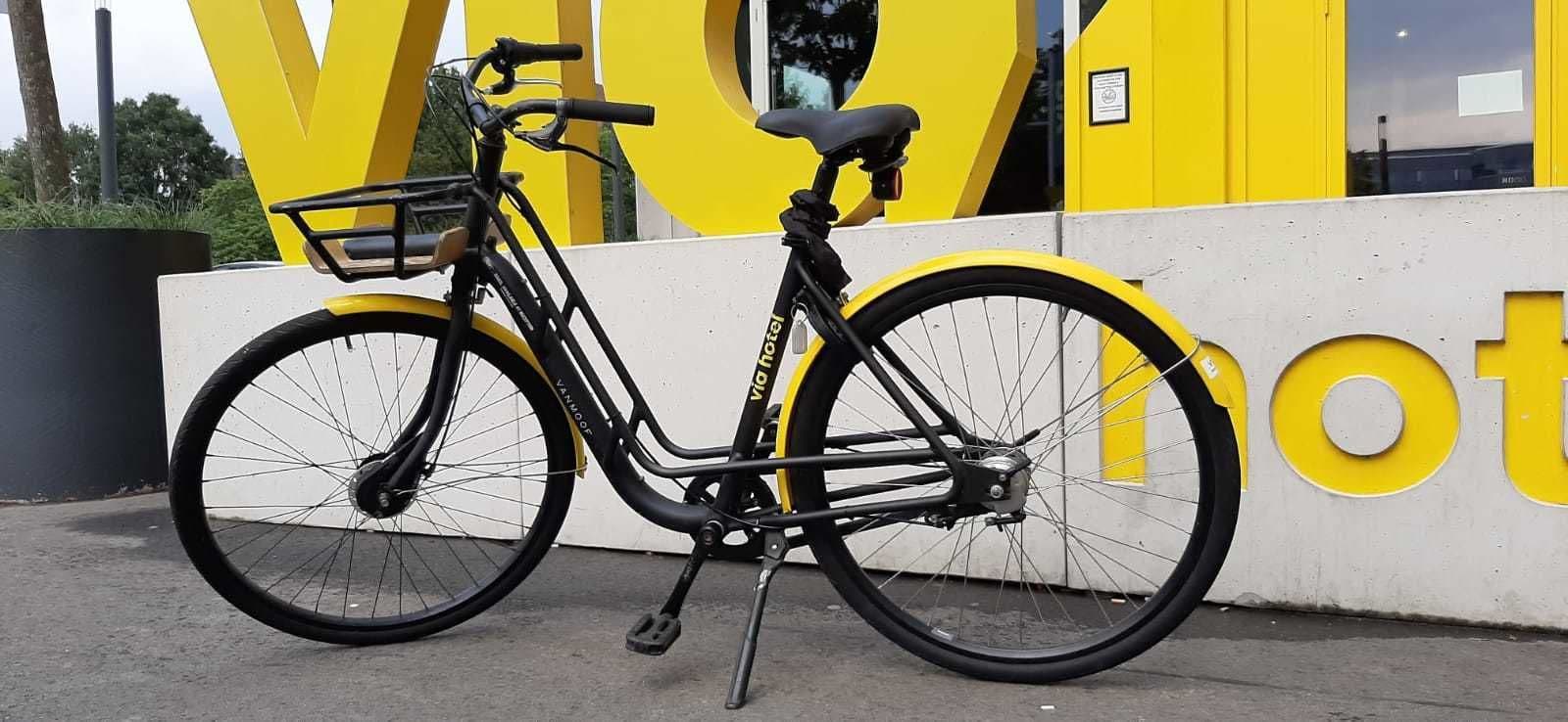 A bicycle parked in front of a building with large yellow letters.