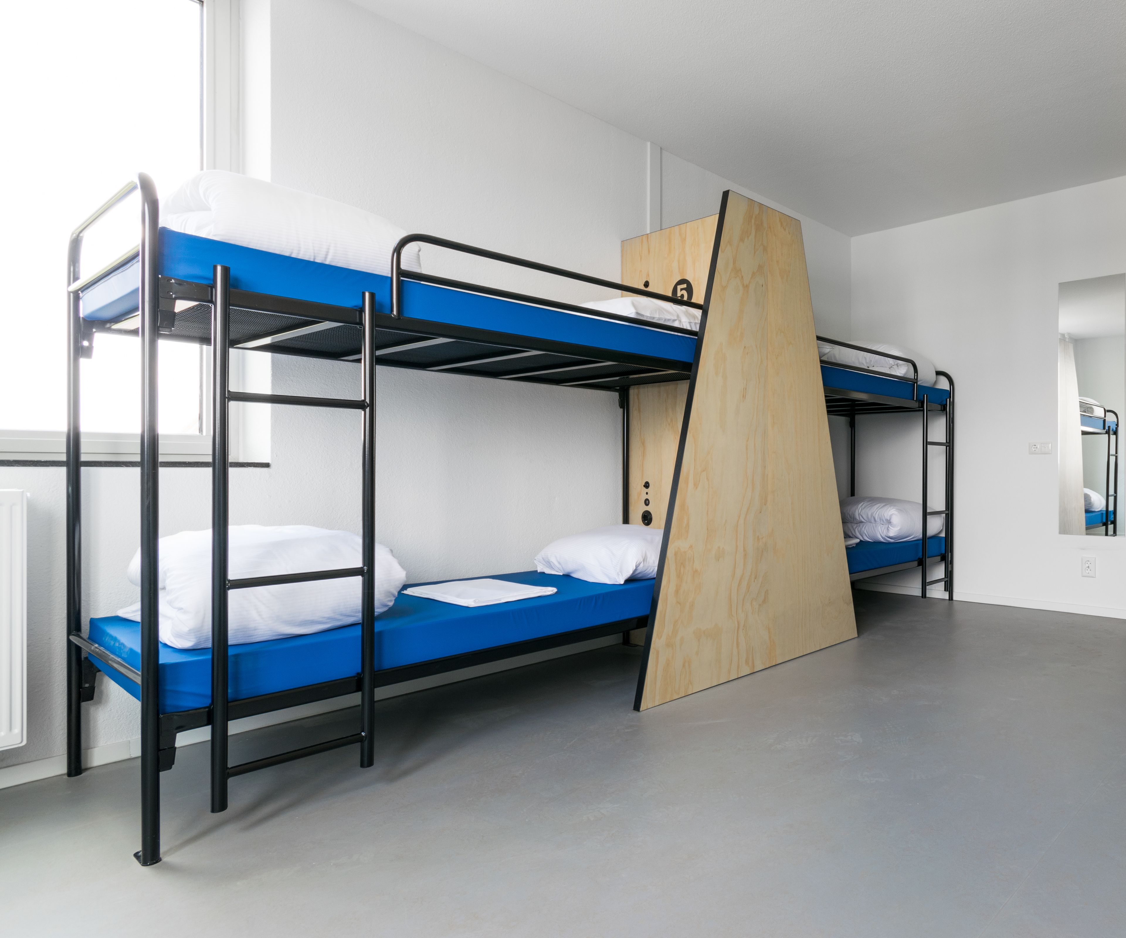 A bunk bed room with a wooden ladder, white bedding, and a grey floor.