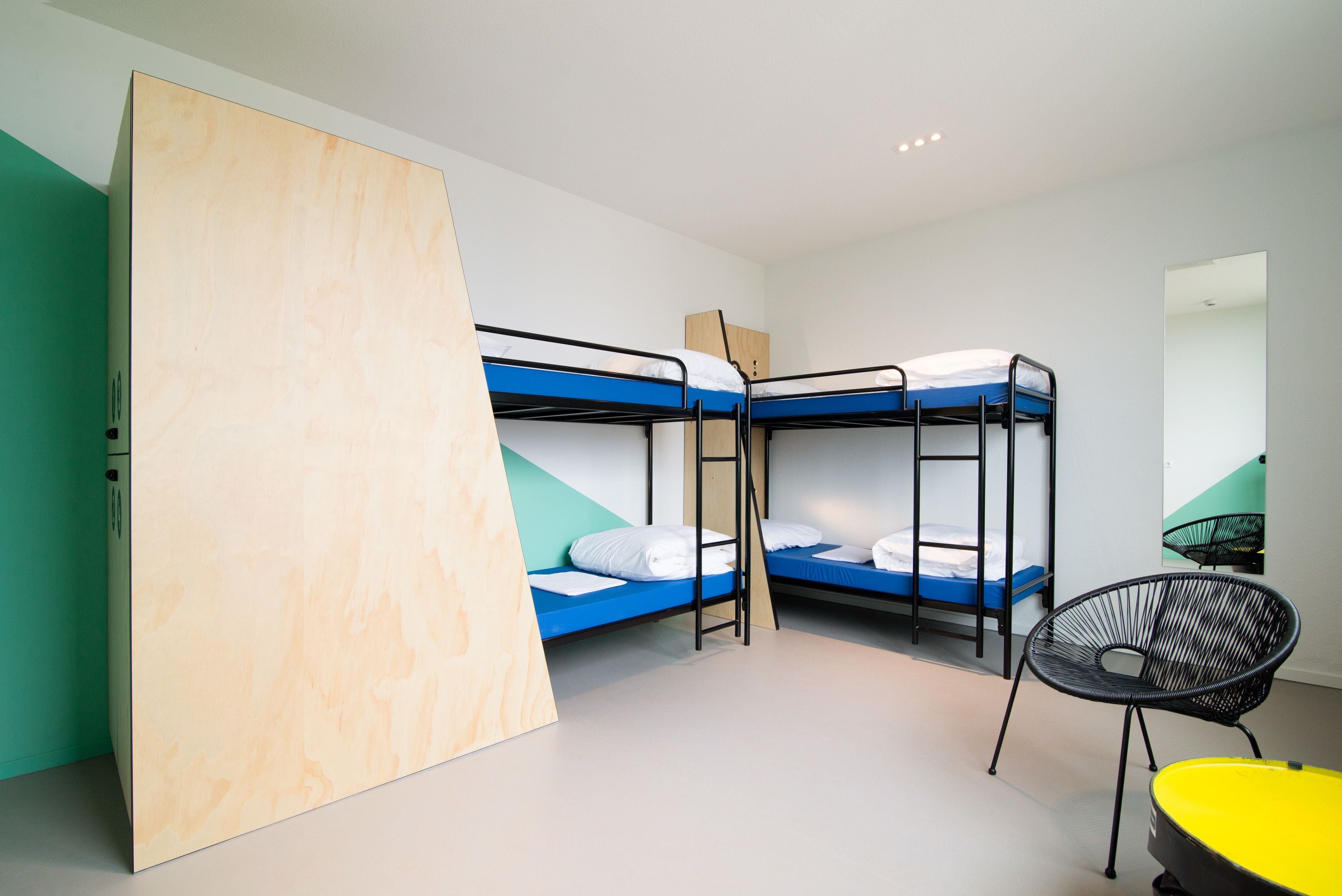 A room with bunk beds, a wooden cabinet, a black chair, and a yellow chair.