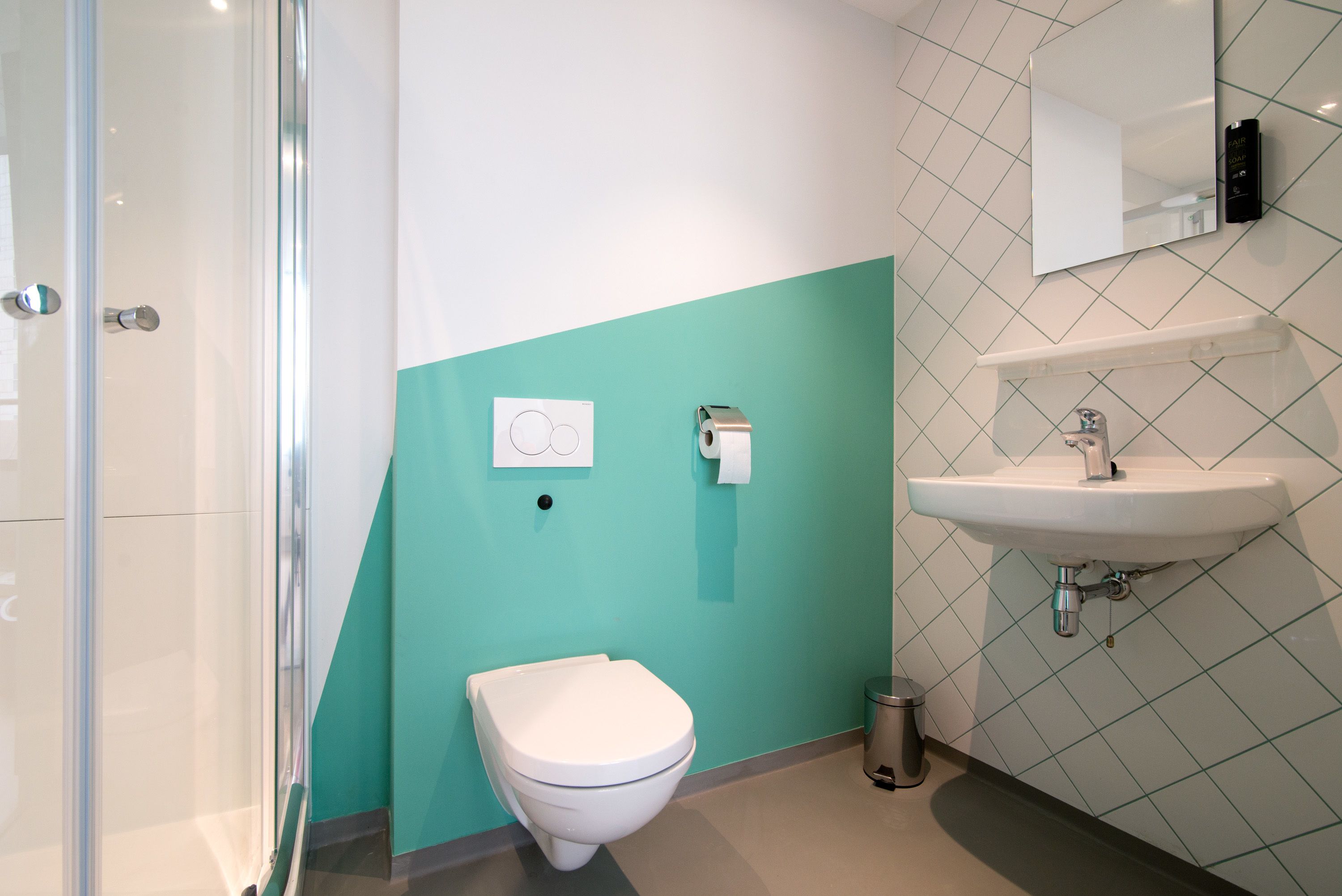 A modern bathroom with a glass shower enclosure, a white toilet, and a sink with a mirror above it.