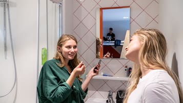Un baño con espejo, lavamanos y ducha.