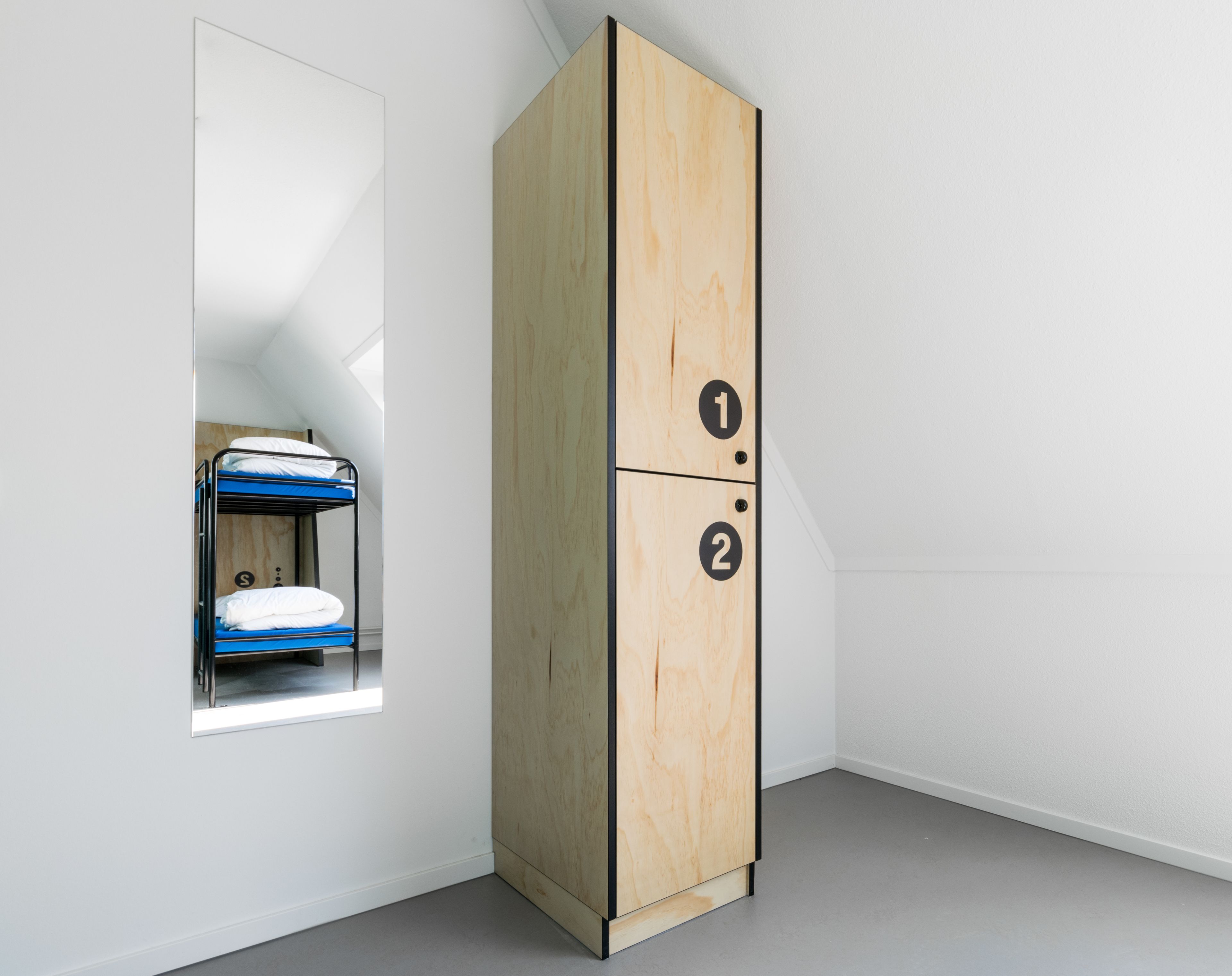 Una habitación con una litera y un armario de madera de dos compartimentos, numerados 1 y 2.