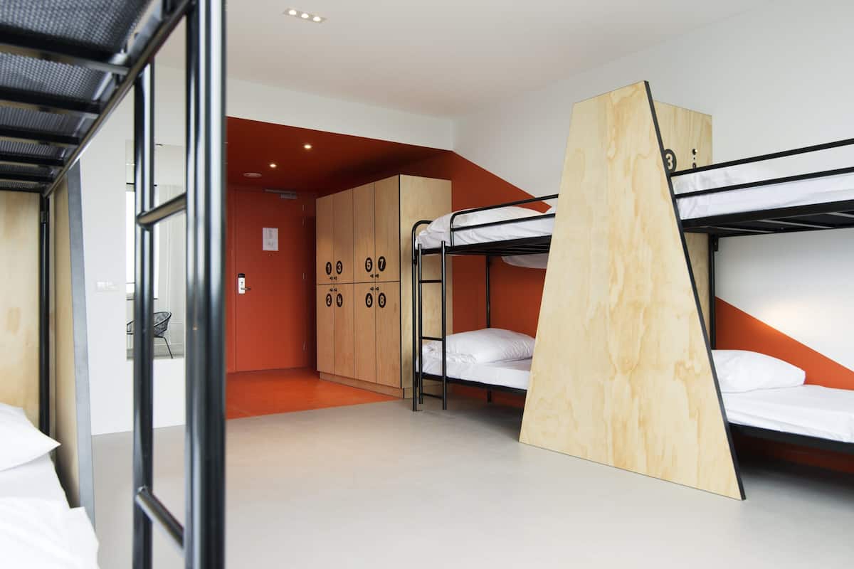 A dormitory room with bunk beds, wooden cabinets, and a small seating area.