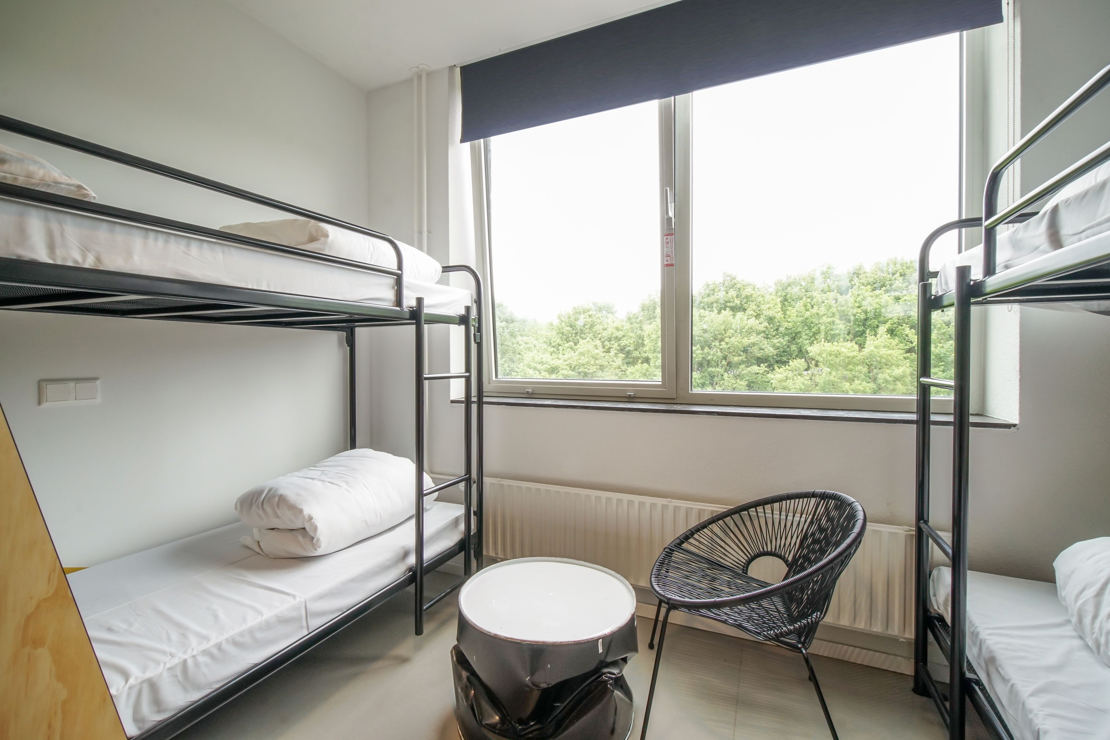 A dormitory room with bunk beds, a round table, and a chair.