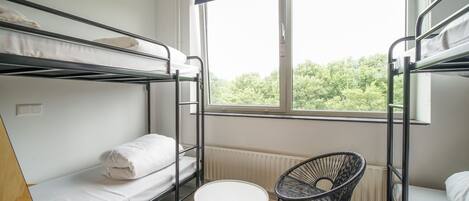 A dormitory room with bunk beds, a round table, and a chair.
