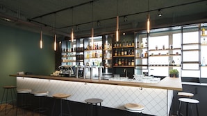 A bar area with a counter, stools, and shelves of bottles and glasses. - Via Amsterdam - Hostel (Diemen)
