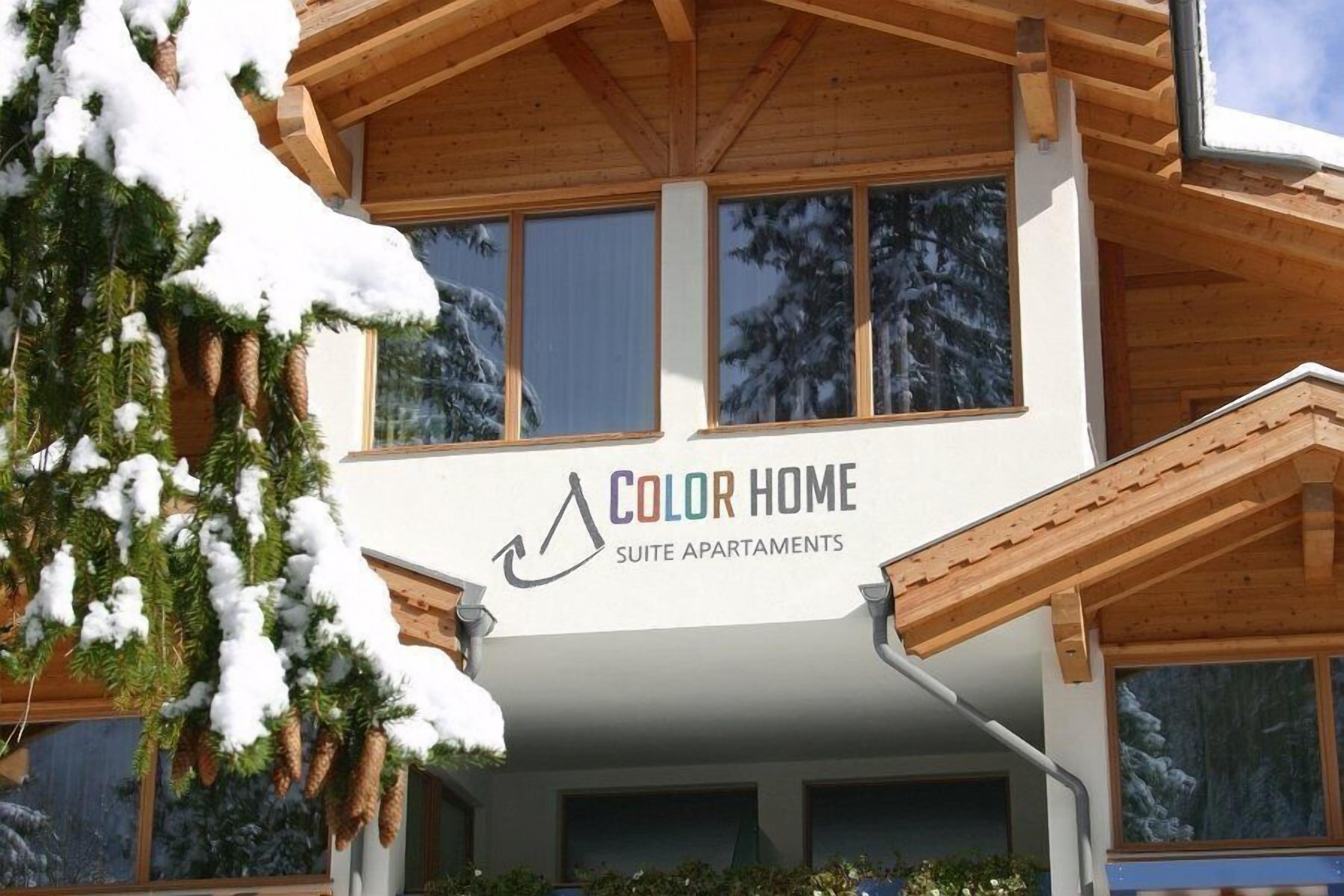 A wooden building with a sign reading "Color Home Suite Apartments".
