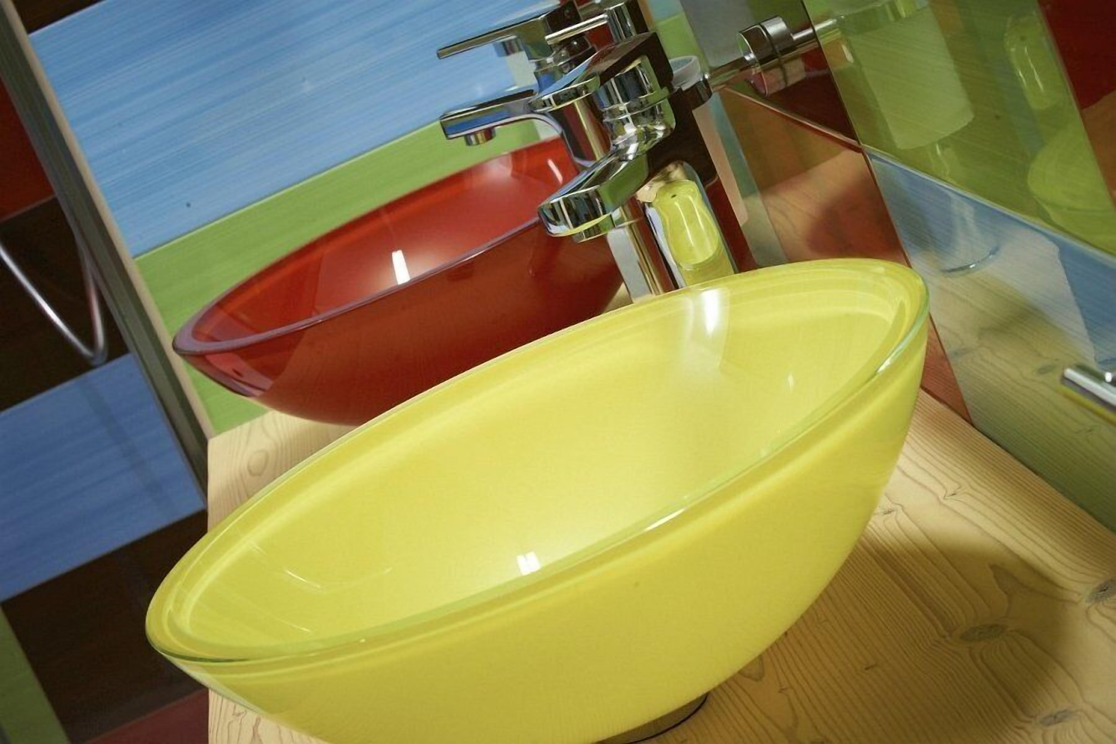 Ein Badezimmer mit einem gelben Waschbecken und einer roten Waschschüssel.