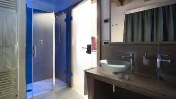 A modern bathroom with a glass-enclosed shower, a wooden vanity with a bowl sink, and a large mirror.