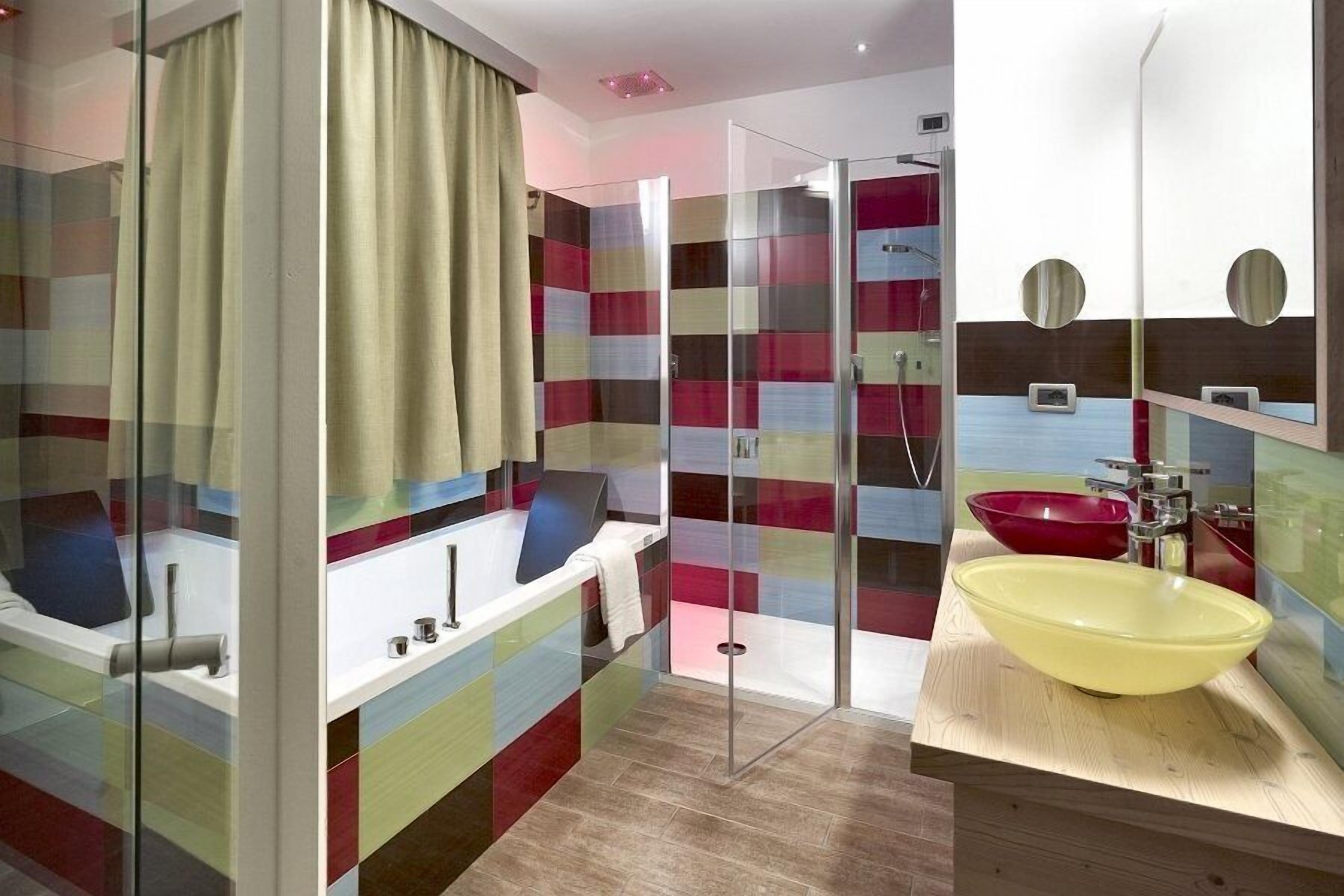 A modern bathroom with a glass shower enclosure, a large yellow sink, and a bathtub with a towel.