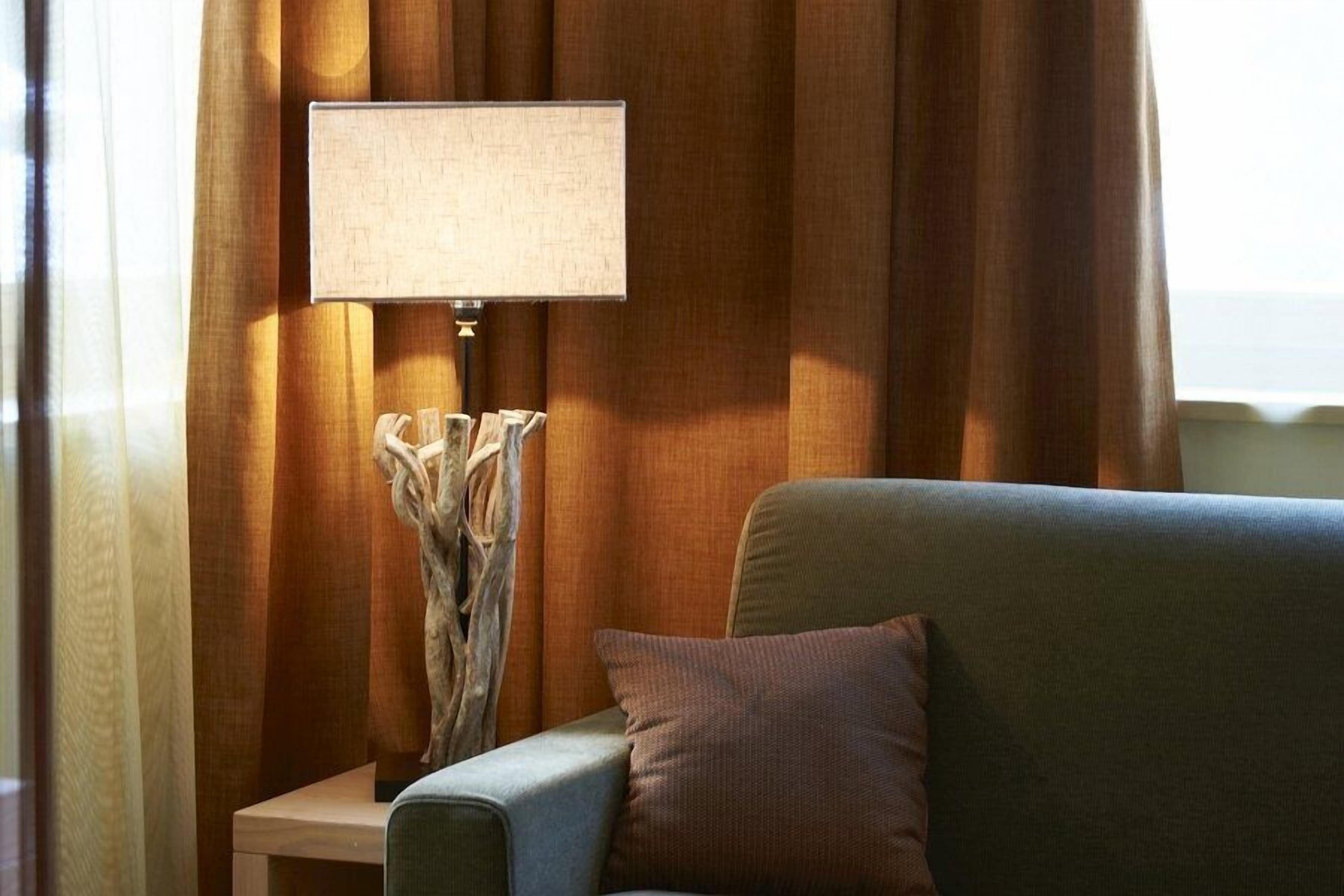 Une pièce avec un canapé, une lampe et des rideaux.