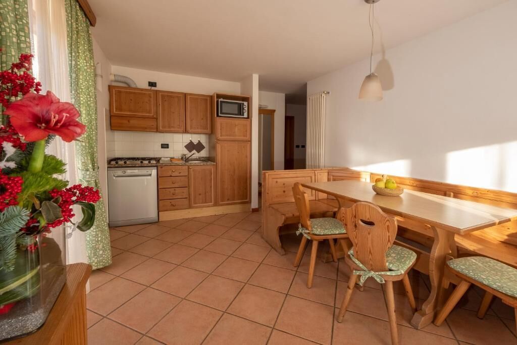 Una cocina con armarios de madera, un microondas y una mesa de comedor con sillas.