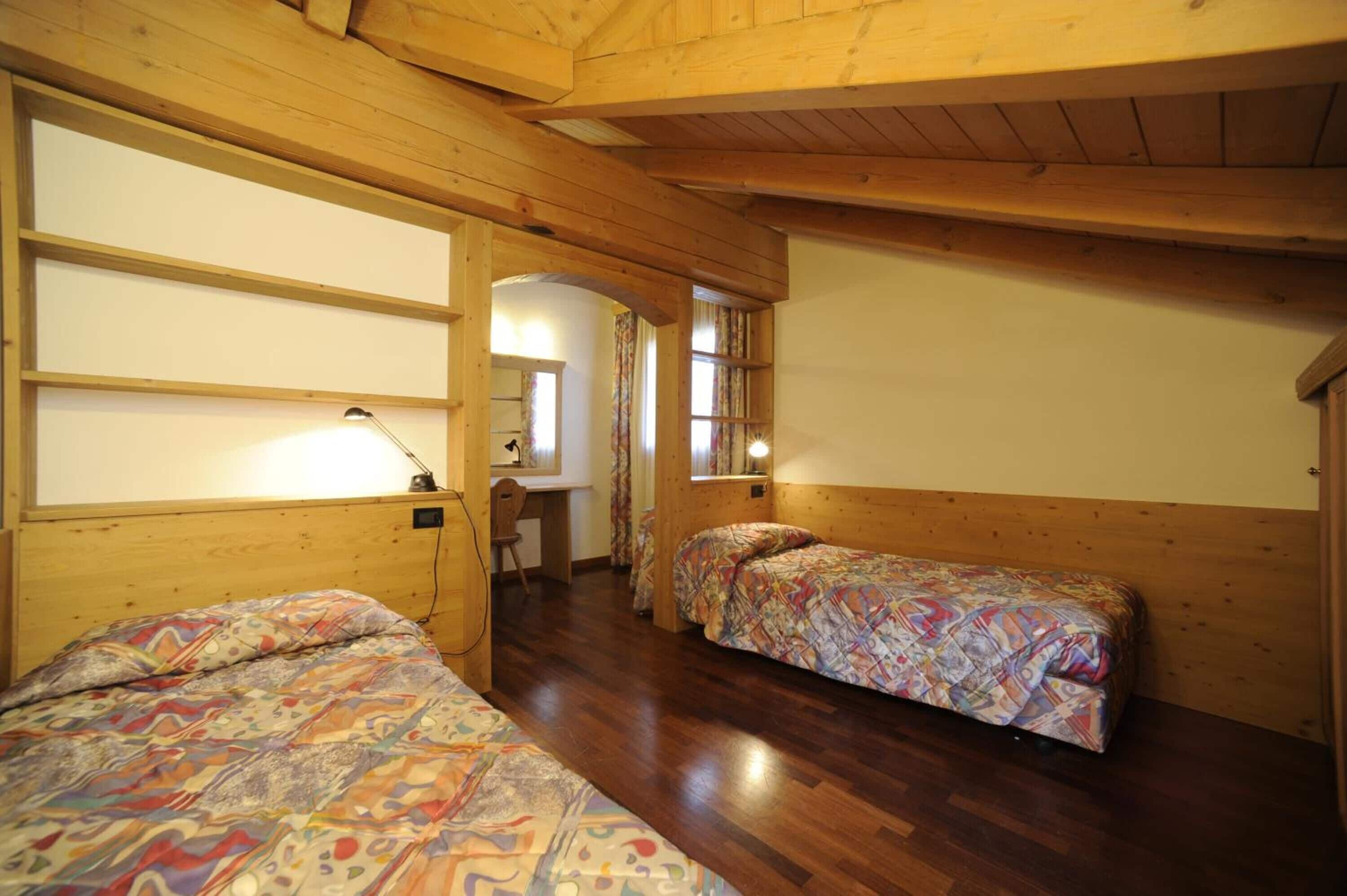 A wooden room with two beds, a desk, and a chair.