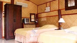 Ein Zimmer mit zwei Betten, Holzmöbeln, einem Fernseher und einer Lampe.