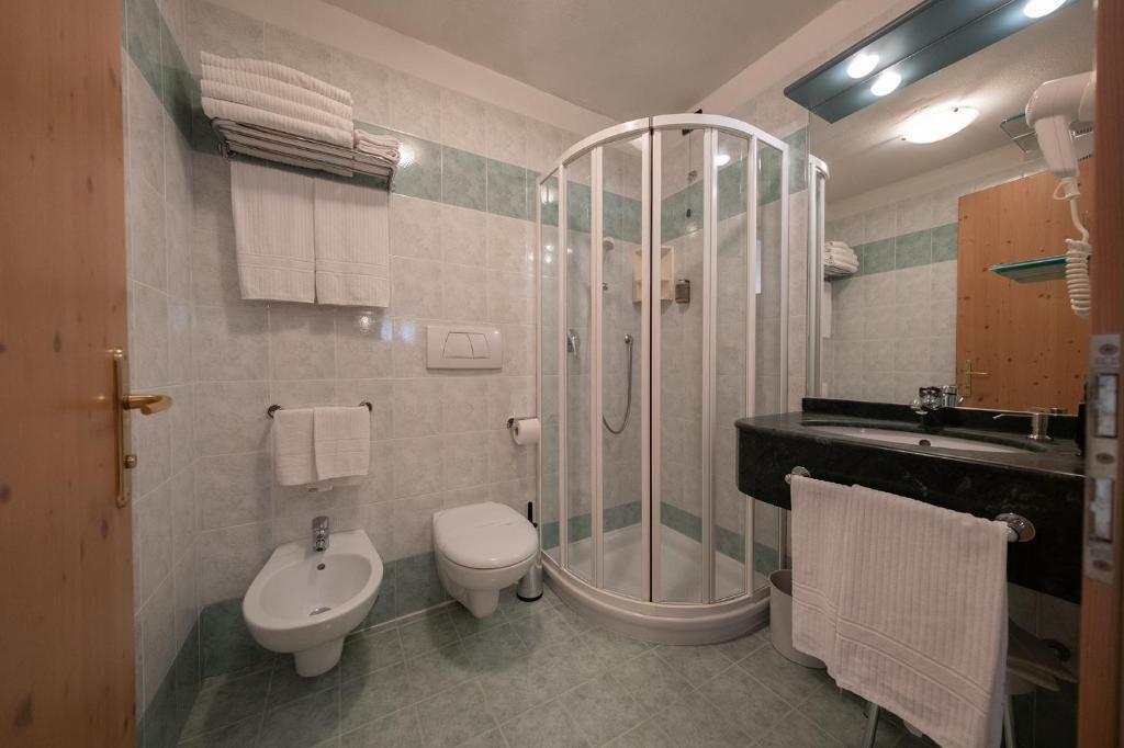 Une salle de bain équipée d’une douche, d’un bidet, de toilettes et d’un lavabo avec un miroir.
