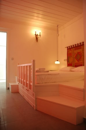 Un dormitorio con cama, mesita de noche, lámpara y aplique de pared.