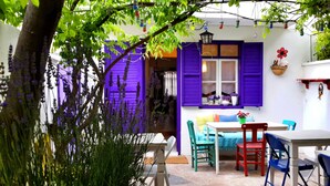 A patio with a table and chairs, purple shutters, and hanging lights. - Amaranda Ada Evi - Adults Only (Bozcaada)
