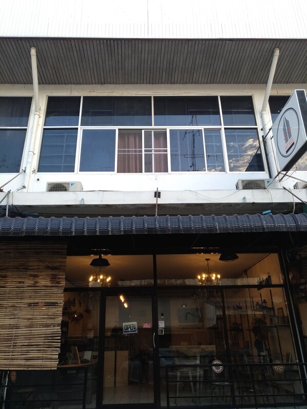 A two-story building with large windows and a sign indicating it is a hostel.