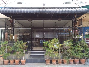 A storefront with a metal awning, glass doors, and potted plants in front.