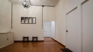 A hallway with wooden flooring, a white door, and a wall-mounted light fixture. - WE Pakchong Hostel (Pak Chong)