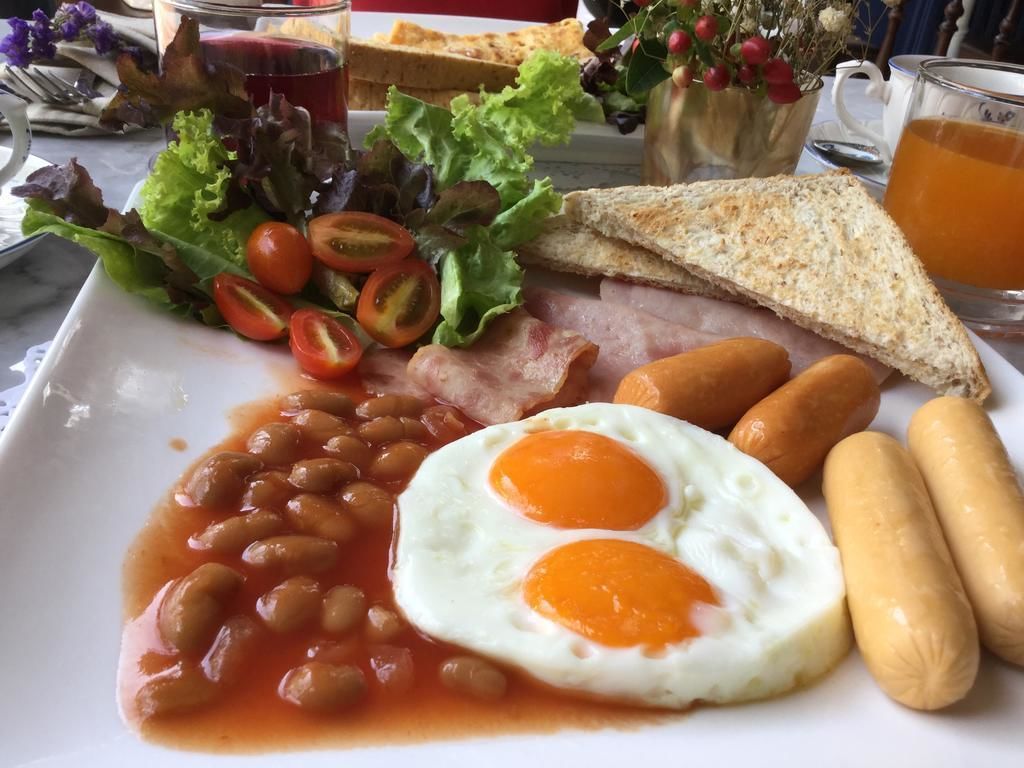 A plate of breakfast food including eggs, beans, sausages, toast, and salad.