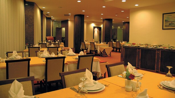 A hotel dining area with multiple tables set for guests, featuring a warm color scheme and modern decor. - Ozkaymak Park Hotel (Konya)