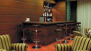 A bar area with striped chairs, a bar counter, and a glass table. - Ozkaymak Park Hotel (Konya)