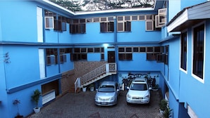 A blue building with two cars parked in front. - Stadium Hotel (Kumasi)