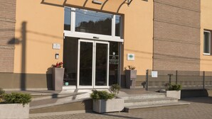 Entrada de un edificio con puerta de vidrio, toldo metálico y señal de estacionamiento.
