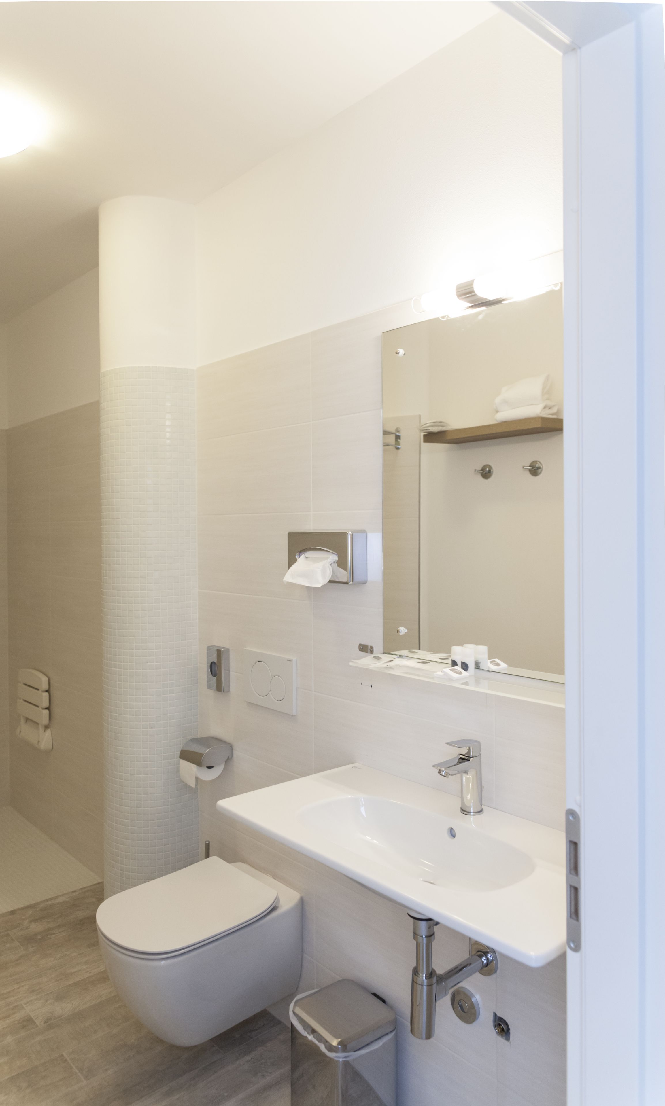 A modern bathroom with a toilet, sink, and mirror.