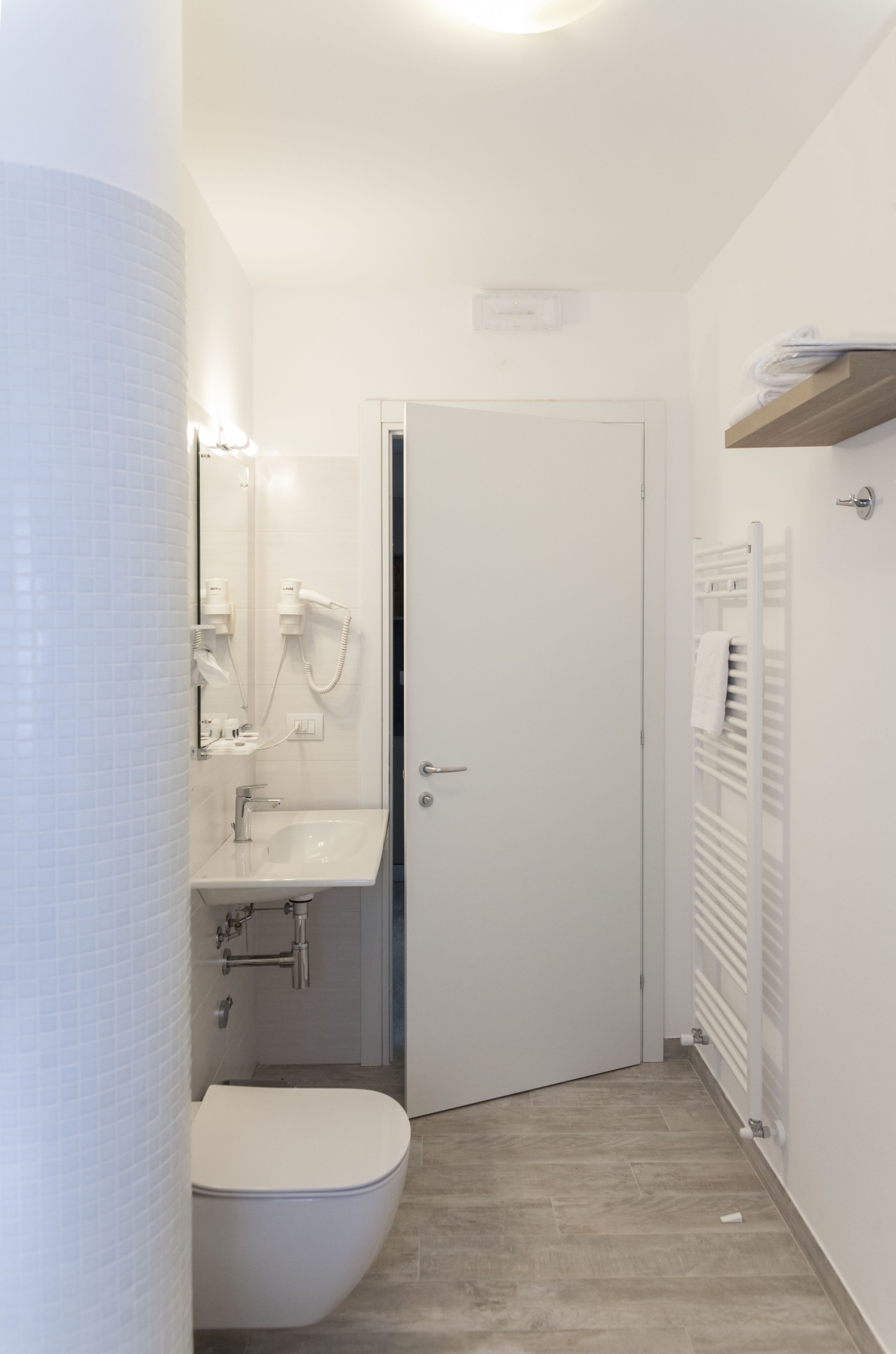 Et lille badeværelse med toilet, vask og håndklædestang.