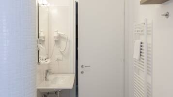 Et lille badeværelse med toilet, vask og håndklædestang.