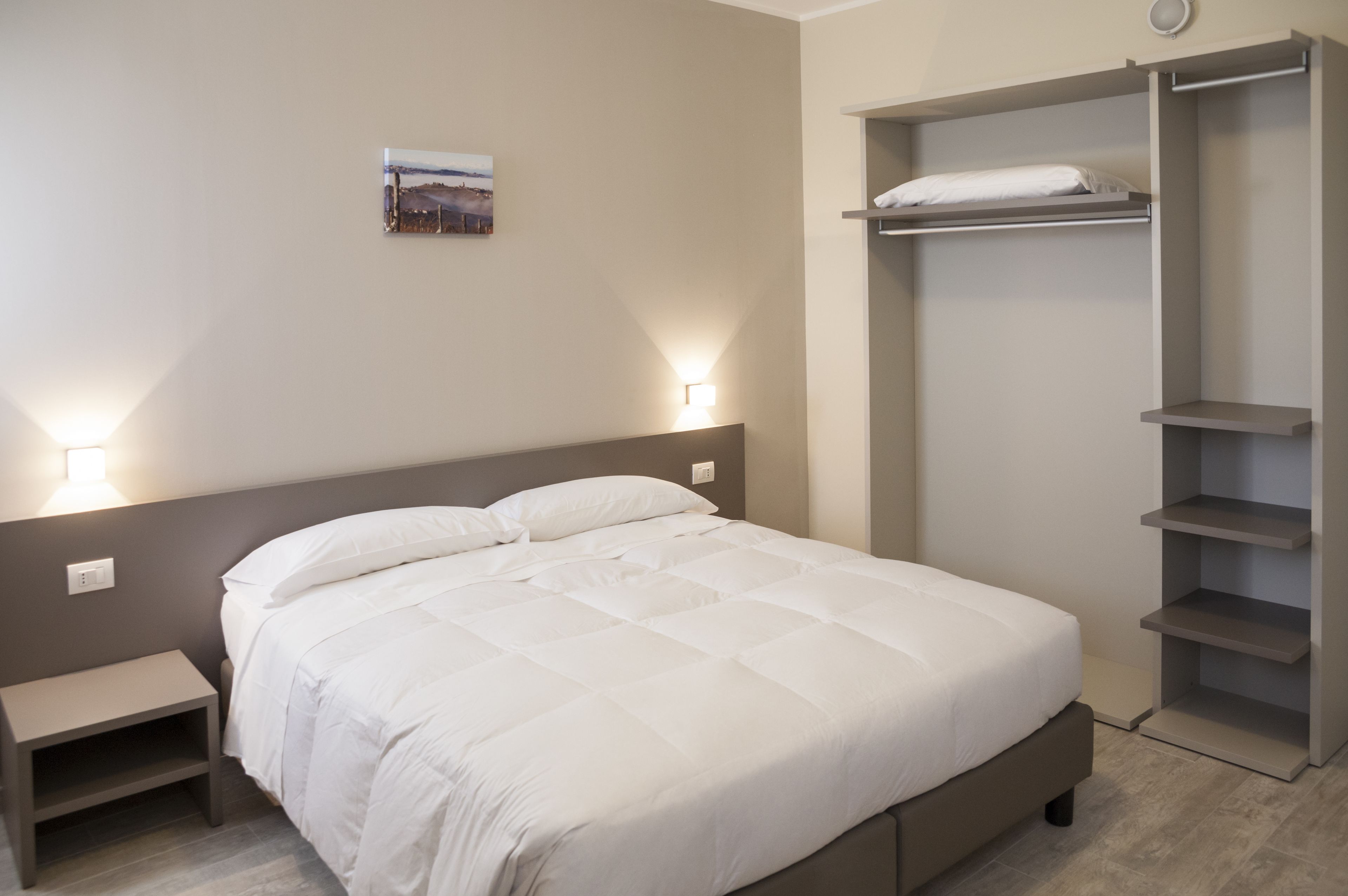 Ein Schlafzimmer mit einem Bett, Nachttischen, einem Wandregal und einem Bild.