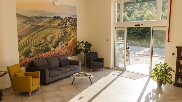 Un hall espacioso con un cuadro de paisaje de grandes dimensiones, un sofá, sillones, una mesa de centro y una planta en maceta.