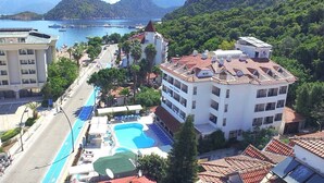 A hotel with a swimming pool, a view of the sea, and a mountainous backdrop. - Portofino Hotel (Marmaris)