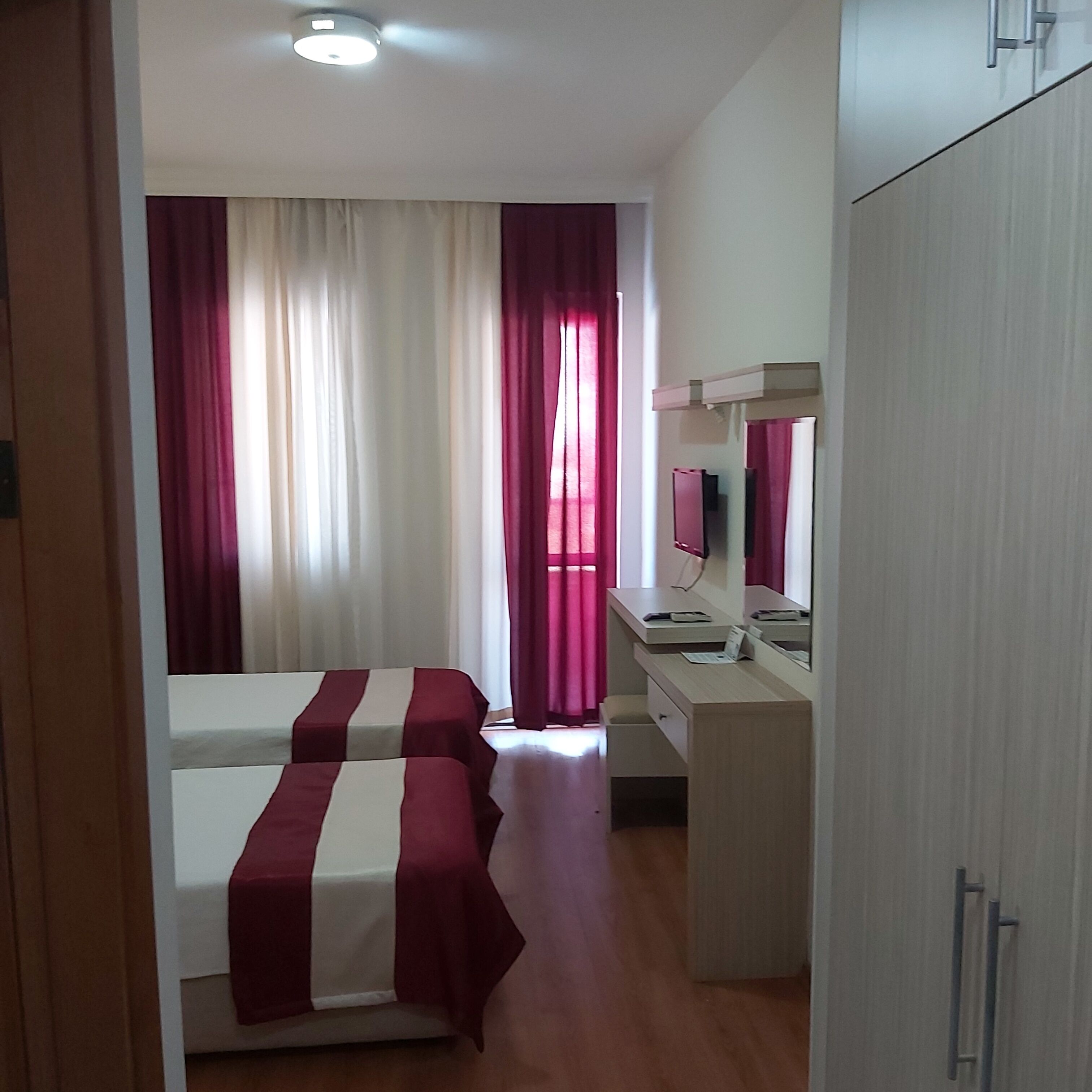 Ein Schlafzimmer mit zwei Betten, einem Schreibtisch, einem Spiegel und einem Kleiderschrank.