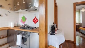 A modern kitchen with stainless steel appliances, a wooden countertop, and a small dining area with a table and chairs. - Veronetta Apartment (Verona)