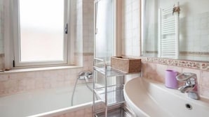 A bathroom with a bathtub, a sink, a mirror, and a window. - Veronetta Apartment (Verona)