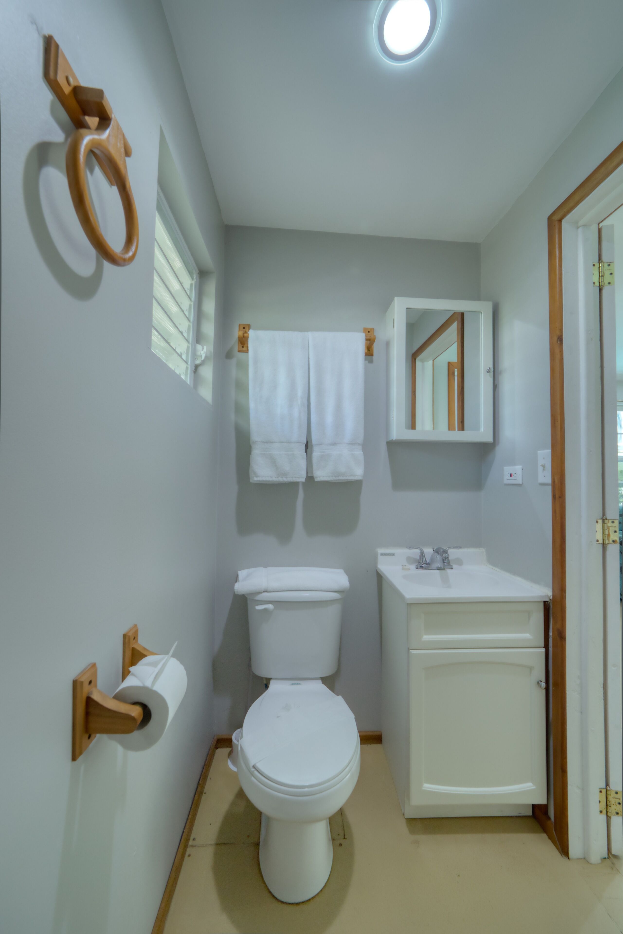 A small, clean bathroom with a toilet, sink, and mirror.