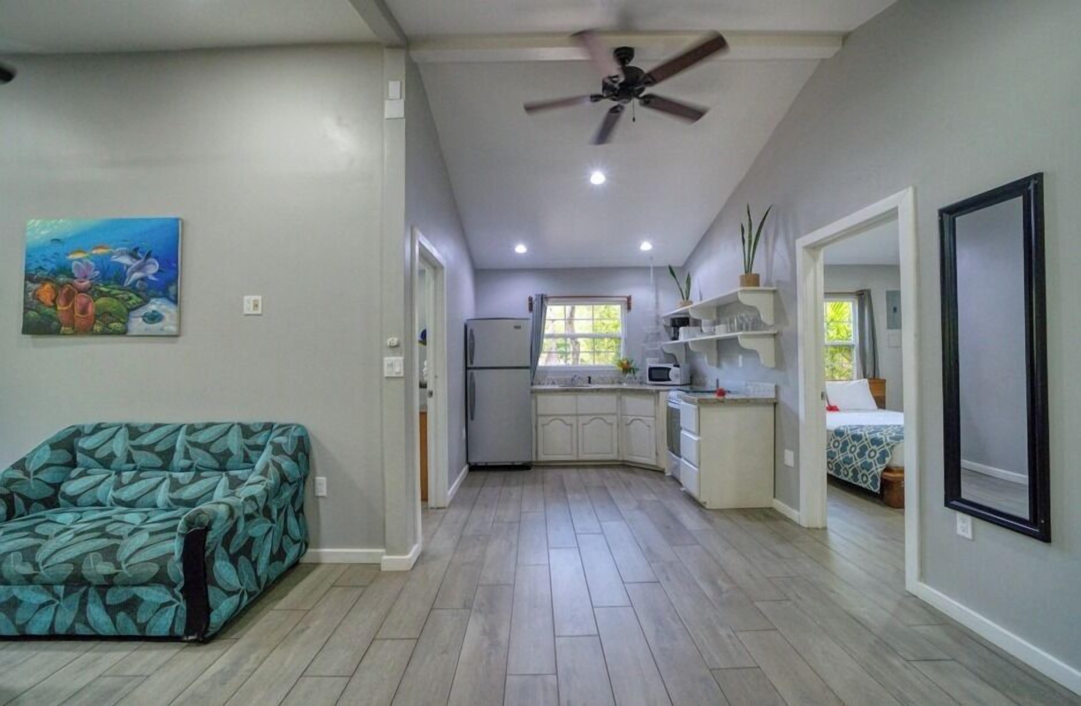A compact kitchen with a refrigerator, microwave, and white cabinets.